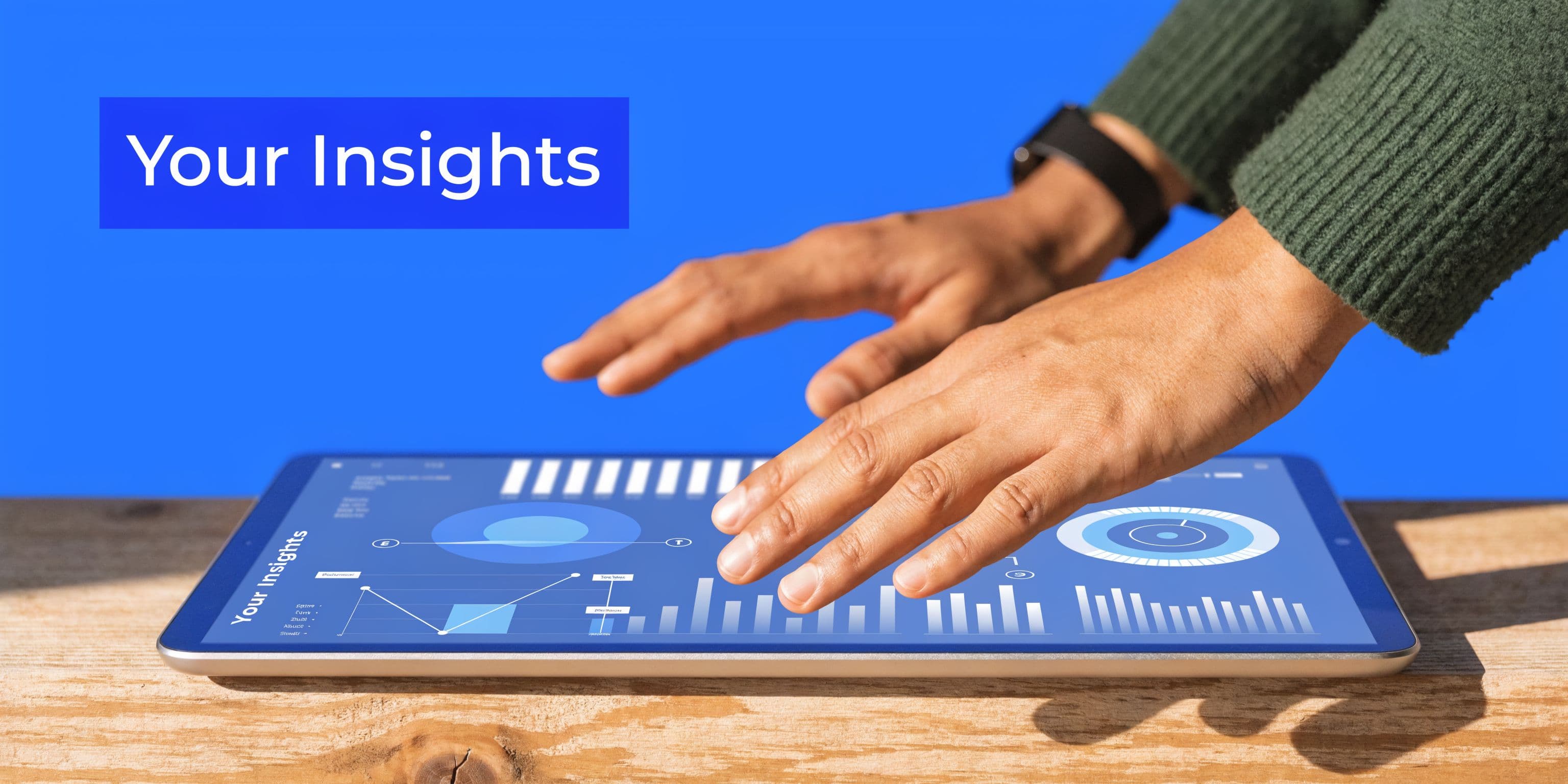A person using a digital tablet to analyze data charts and business insights on a wooden table.